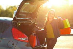 caucasien femme en mettant sa achats Sacs dans le voiture tronc photo