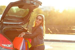 caucasien femme en mettant sa achats Sacs dans le voiture tronc photo