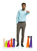 africain américain homme avec achats Sacs et en portant crédit carte sur blanc Contexte. achats photo