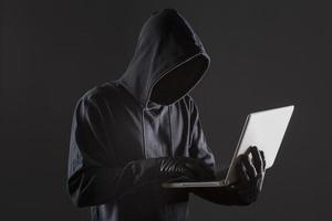 Vue latérale du hacker masculin avec des gants et un ordinateur portable