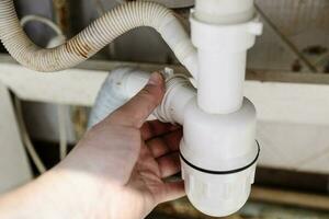 plombier démonte un siphon proche en haut dans cuisine photo