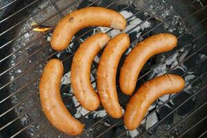 saucisses sur le gril. chaud été vacances barbecue faire la fête. grillage saucisse sur chaud charbon. un barbecue fête avec copains sur les vacances. photo