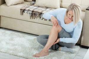 âge moyen femme Souffrance de douleur dans jambe à maison, fermer. physique blessure concept. photo