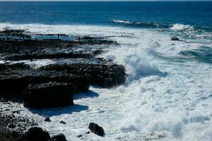 grand vagues s'écraser contre le rochers dans le océan photo