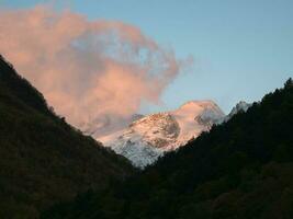 rose des nuages illuminé par le soir Soleil plus de le neige Montagne. cumulus rose coloré des nuages plus de le hiver montagnes. photo