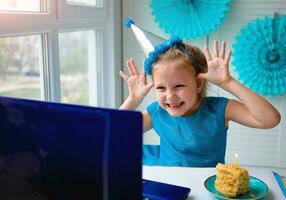 une peu fille, courbes et des rires dans de face de une portable dans une casquette. fête anniversaire via l'Internet dans quarantaine temps, auto-isolement et famille valeurs, en ligne anniversaire. toutes nos félicitations à le animateur photo