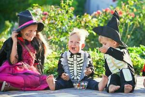 Jeune des gamins tour ou traiter pendant Halloween . les enfants sont séance sur le route dans Halloween déguisements. copie espace photo