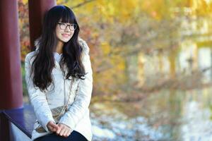 jolie chinois fille Robes vers le bas manteau dans le ensoleillement journée photo