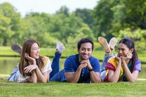 un groupe d'amis étudiants est allongé sur l'herbe sur le campus de l'université près du lac pour les loisirs et le concept de style de vie de bonheur photo