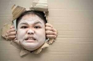 fantôme enfant en colère et à la recherche par trou sur papier carton. photo