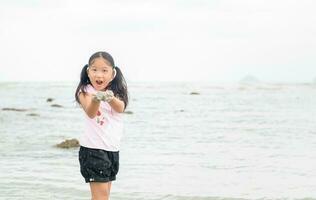 peu fille jouer le sable sur le plage, photo