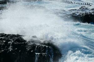 grand vagues s'écraser contre le rochers dans le océan photo