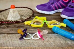 des sports équipement le birdie est sur le raquette, saut corde, nager des lunettes de protection et baskets sur en bois Contexte photo