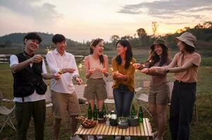 groupe de Jeune asiatique gens sont prendre plaisir camping , en jouant cierge magique dans Naturel site de camp à crépuscule photo