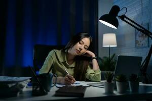 Jeune fatigué femme d'affaires travail dans le nuit décalage à maison. photo
