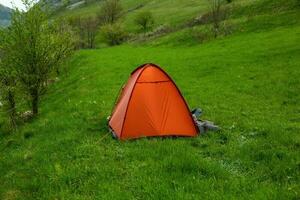 camping tentes sur une vert Prairie dans le montagnes dans printemps. du repos avec le tente dans la nature photo