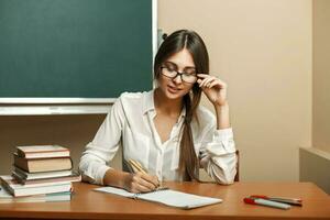 magnifique Jeune femme avec des lunettes à étude à université, en train de lire livres et écrit dans une carnet. photo