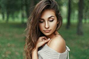 jolie Jeune fille avec le coiffure dans ancien élégant chandail regards vers le bas photo