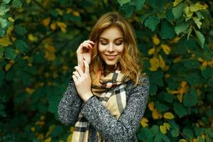 magnifique content fille dans une ancien écharpe et manteau sur une vert jaunâtre feuillage. photo