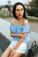 asiatique femme dans une bleu chemisier et blanc short avec une sac photo