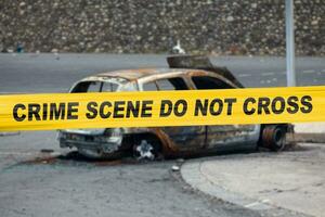 américain police ruban barricader une brûlé voiture photo