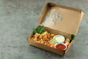 papier boîte avec savoureux frit pop corn poulet sur gris Contexte photo