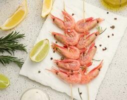 crevettes enfilé sur en bois des bâtons, soja sauce et épices sur une blanc tableau, Haut vue photo