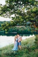 Fille blonde aux cheveux lâches dans une robe bleu clair et un mec à la lumière du coucher du soleil photo