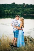 Fille blonde aux cheveux lâches dans une robe bleu clair et un mec à la lumière du coucher du soleil photo