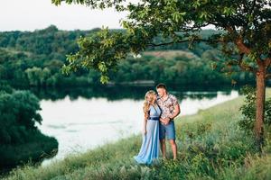 Fille blonde aux cheveux lâches dans une robe bleu clair et un mec à la lumière du coucher du soleil photo