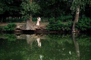 un mec et une fille marchent le long des rives d'une rivière sauvage envahie par la végétation photo