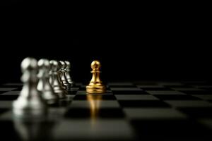 pion d'échecs doré debout devant d'autres échecs, le concept d'un leader doit avoir du courage et du défi dans la compétition, le leadership et la vision commerciale pour gagner dans les jeux d'entreprise photo
