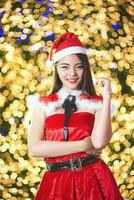 jolie asiatique fille dans Père Noël costume pour Noël avec nuit lumière photo