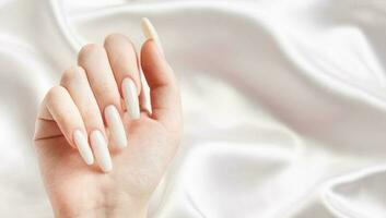 une femme mains avec une manucure sur eux, le ongles sont peint dans une blanc couleur. photo