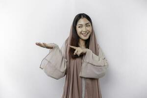 Jeune asiatique musulman femme souriant tandis que montrer du doigt à copie espace à côté de sa photo