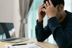 homme asiatique stressé et mal à la tête avec de grosses factures ou factures pas d'argent à payer pour les dépenses et la dette de carte de crédit. pénurie, problèmes financiers, hypothèque, prêt, faillite, faillite, pauvre, portefeuille vide photo