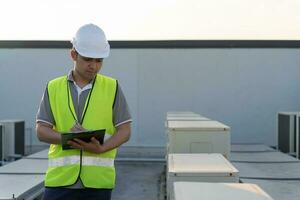 asiatique entretien ingénieur travaux sur le toit de usine. prestataire inspecter compresseur système et des plans installation de air état systèmes dans construction. liste de contrôle, inspecteur, contrôle photo