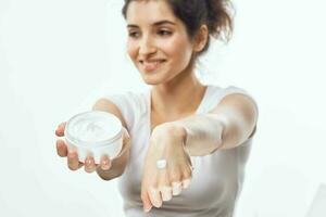 femme dans blanc T-shirt crème pot peau se soucier hydratant dermatologie photo