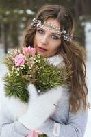 magnifique la mariée dans une blanc robe avec une bouquet dans une couvert de neige hiver forêt. portrait de le la mariée dans la nature. photo