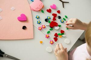 une blogueur fille fait du une se sentait artisanat pour la Saint-Valentin journée dans le forme de une cœur. le concept de enfants la créativité et Fait main. photo