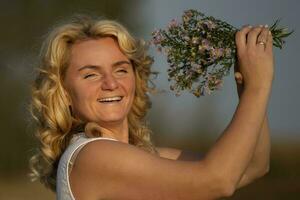 magnifique âge moyen blond avec une bouquet de fleurs sauvages avec une sourire. photo