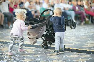 peu les enfants jouer sur le rue avec une poussette. photo