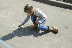 Biélorussie, Gomel, mai 30, 2019. un ouvert journée dans une Jardin d'enfants. une préscolaire fille dessine sur le asphalte avec craie. photo