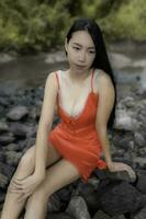 portrait de sexy asiatique femme à le chute d'eau, sentiment Frais à le rivière, thaï femelle se détendre à pays photo