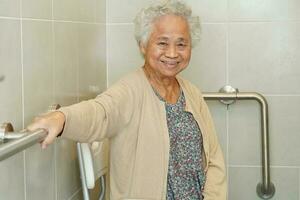 une vieille femme asiatique âgée utilise un rail de support de toilette dans la salle de bain, une barre d'appui de sécurité pour main courante, la sécurité dans l'hôpital de soins infirmiers. photo