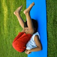 asiatique intelligent enfant Faire yoga pose dans le société parc Extérieur, enfants yoga pose. le peu garçon Faire yoga et méditation exercer. photo