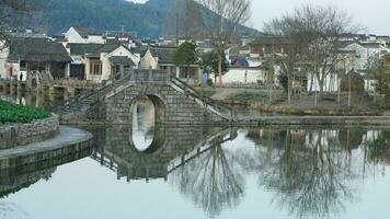 un vieux traditionnel chinois village vue avec le vieux arqué pierre pont et vieux en bois bâtiments dans le du sud campagne de le Chine photo