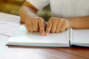 visuellement altéré la personne lit avec le sien les doigts une livre écrit dans braille il est écrit pour ceux qui sont visuellement altéré ou aveugle. il est une spécial code généré de 6 points dans le boîte. photo