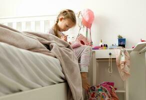 une peu fille écrit dans sa journal intime dans sa chambre. désordre autour photo