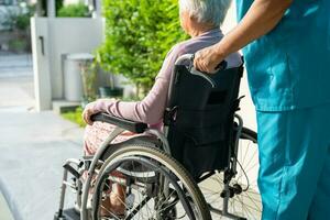 soignant aide et soins asiatique senior ou âgée vieille dame patiente assise sur un fauteuil roulant jusqu'à la rampe dans l'hôpital de soins infirmiers, concept médical fort et sain. photo